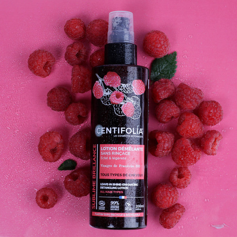 Front view of the Centifolia Leave-in Shine-Enhancing Detangling Lotion with raspberries around it, which are a key ingredient