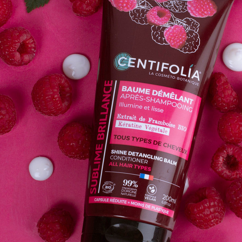 Close up of Centifolia Shine Detangling Balm with dots of the product and raspberries scattered around signifying they are a key ingredient