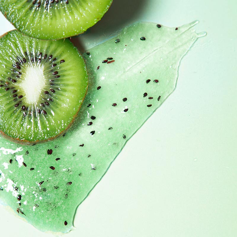 Close up shot of Kiwi slices with a smear of kiwi seeds in a green gel, which are a key ingredient for the Centifolia Exfoliating Detox Gel
