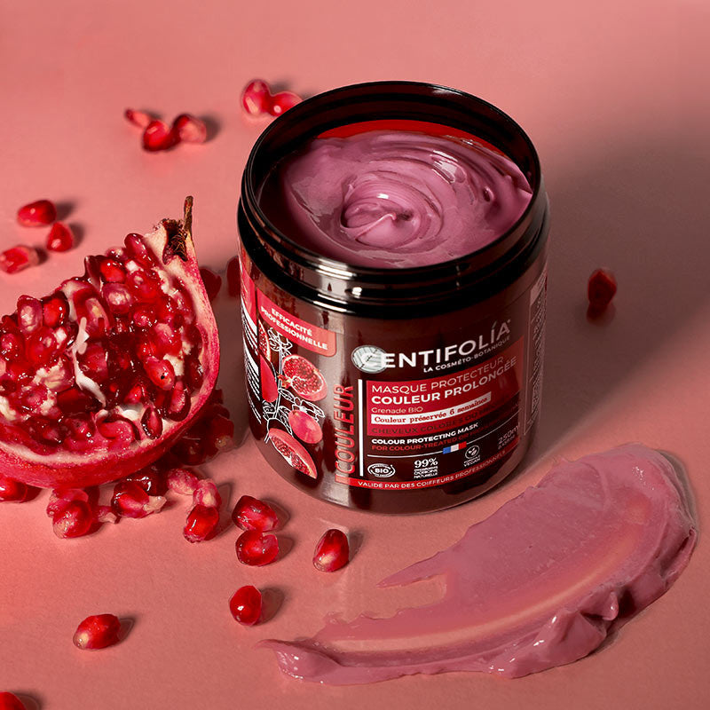 Centifolia Long-Lasting Colour Protecting Mask tub with the lid off showing the pink cream like substance inside. Pomegranate seeds scattered around the tub. 