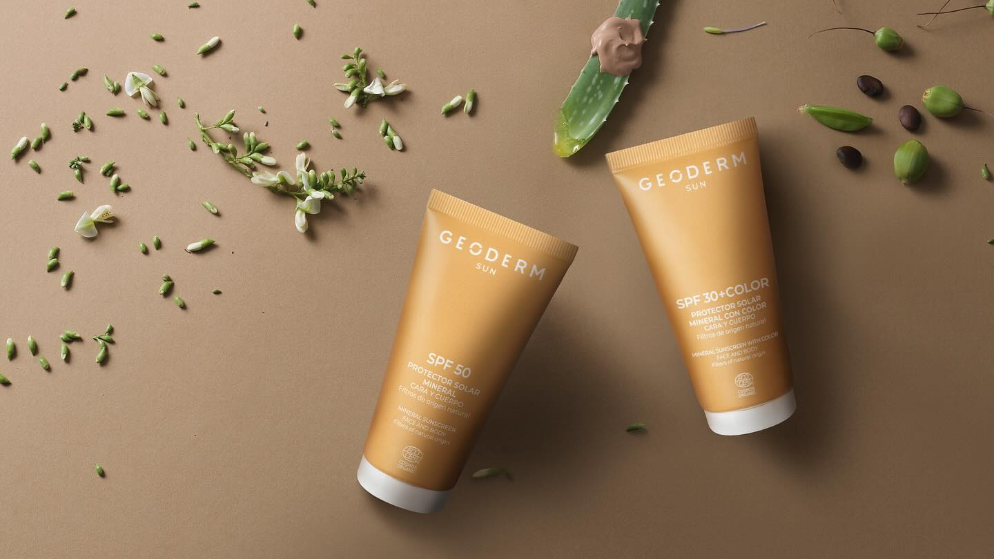 Two GeoDerm skincare products on a brown background with green leaves and seeds.